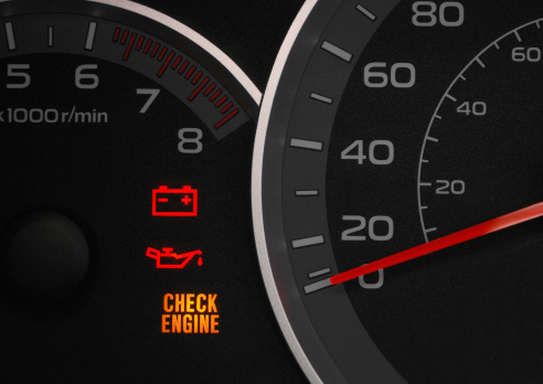Close up on a cluster with the check engine warning light on indicating a car failure.