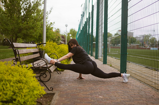 Sportswoman stretches body doing splits on wooden bench