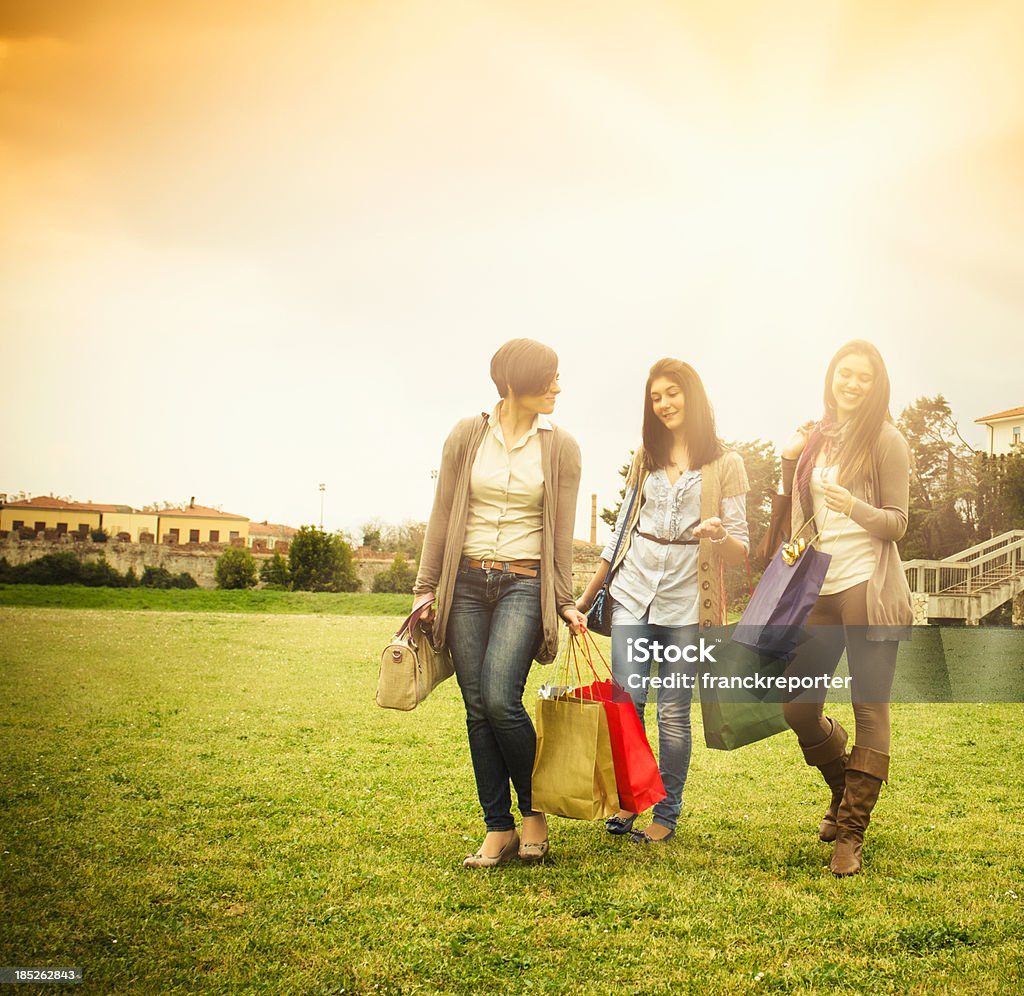 少女たちとショッピングバッグ、草の上を歩く - 小売りのロイヤリティフリーストックフォト