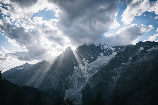 Sun ray beams through clouds over glaciated mountain