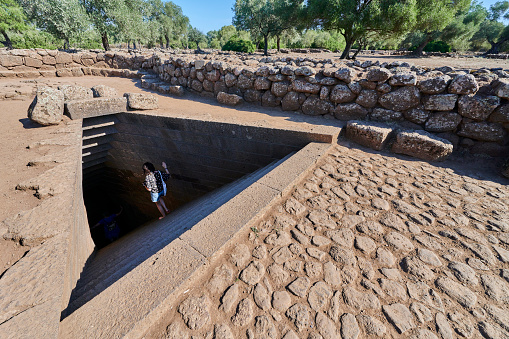 Paulilatino, Italy - October 1, 2023: A woman descending into the sacred well of Santa Cristina, a 25th century BC construction and nuragic site.