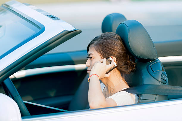 азиатская женщина вождение и говорит на cellphone - car phone стоковые фото и изображения