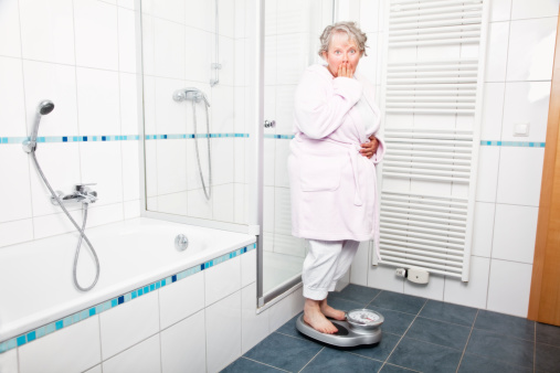 senior woman, 58 years old, in bathroom, onscale, embarrassed about overweight