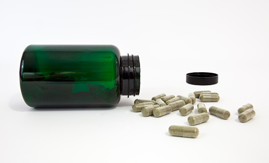Green supplement/vitamin bottle with cap and capsules. Vertical. White background. NO PS ISOLATION. Horizontal.-For more jars, boxes, containers, bottles, and bags click here.  JARS, BOXES, CONTAINERS, BOTTLES, and BAGS 