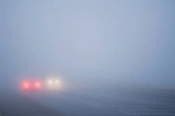 Cars driving slowly in thick fog with plenty of copy space.