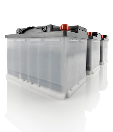 Line of three car batteries, isolated on white reflective surface. Two clipping paths (for batteries and reflection) included.