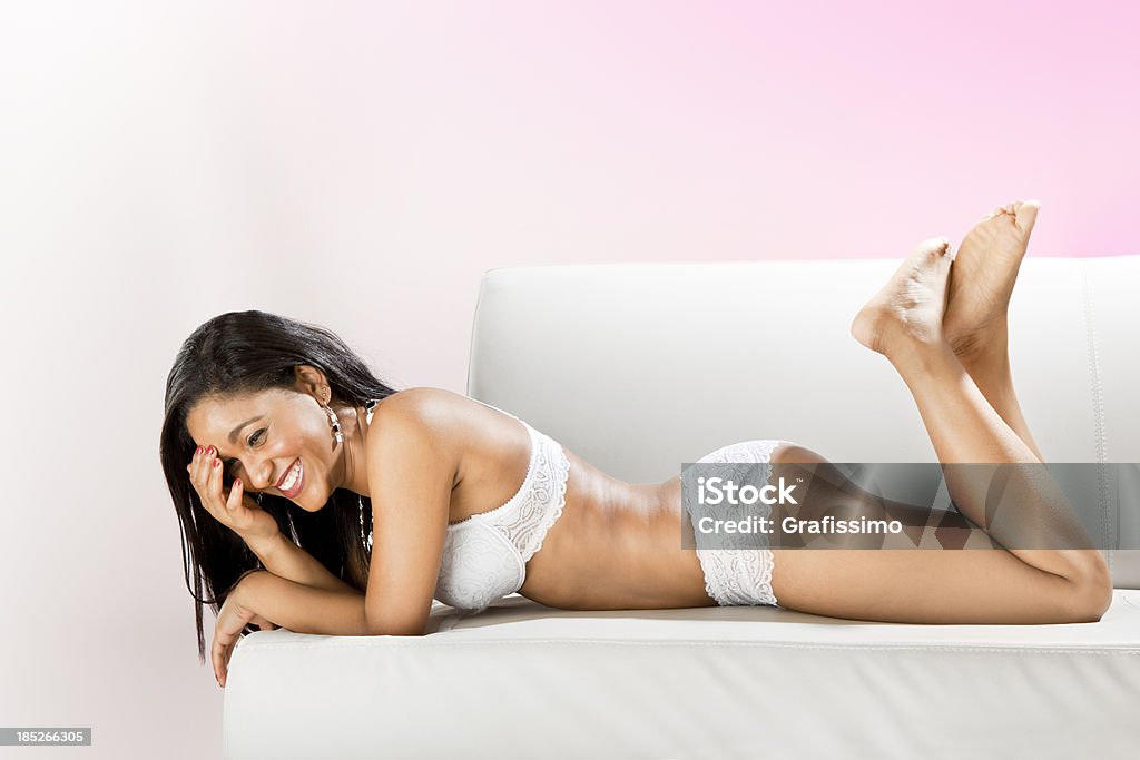 Modella brasiliana ridendo sdraiata in lingerie sul divano - Foto stock royalty-free di 20-24 anni