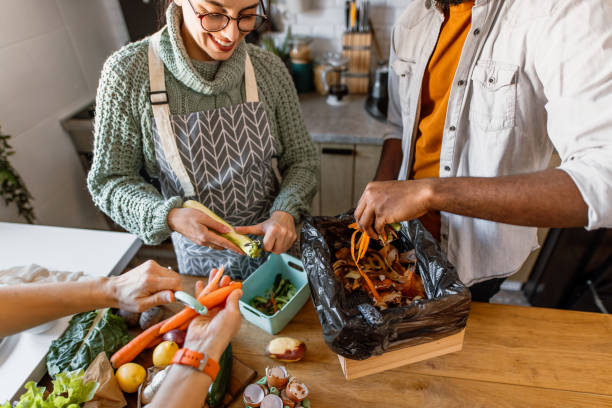 istock Group of friends colecting organic waste in compost bin while preparing lunch in the kitchen 1852664940