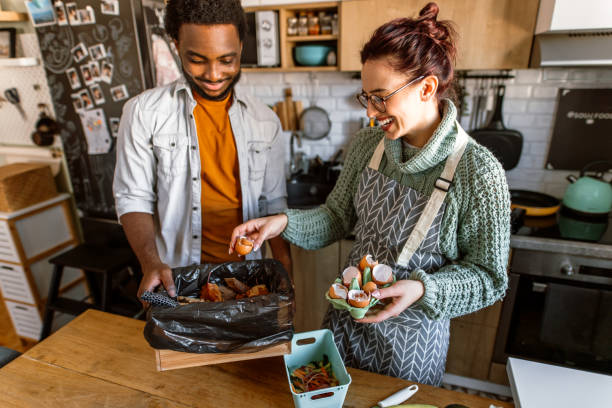 istock Group of friends colecting organic waste in compost bin while preparing lunch in the kitchen 1852666769