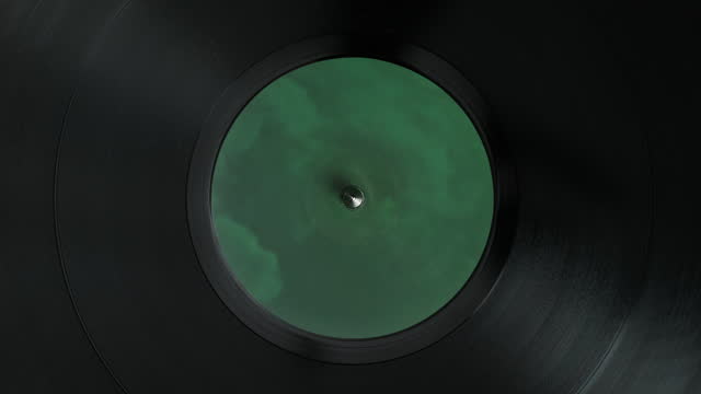 Spinning Vinyl Record in Close up - Top View of the Turntable Spindle and a Green Label