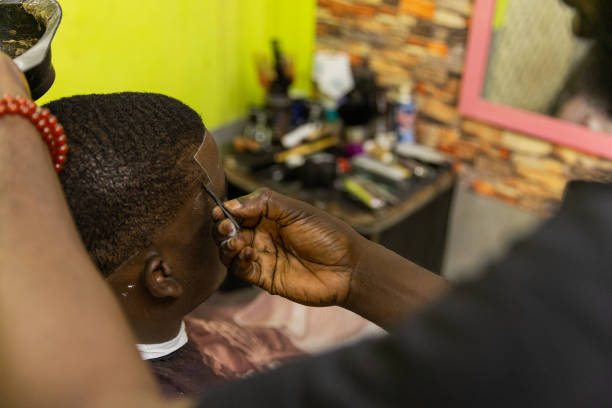 An African barber applies hair dye to his customer in the barbershop An African barber applies hair dye to his customer in the barbershop. black barber stock pictures, royalty-free photos & images
