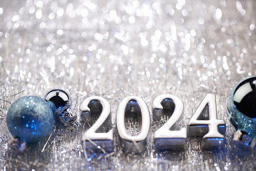 Embrace the transition with this bright and abstract New Year stock photo. The chrome 2024 reflects against a white background, surrounded by sparkling snowflake shapes, creating a dazzling celebration of change.. Native image size: 7952x5304