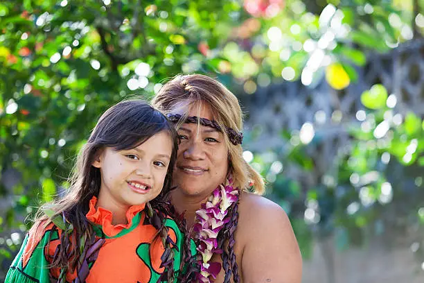 Hawaiian mother and daughter in traditional Hawaiian clothing with leis around their necks