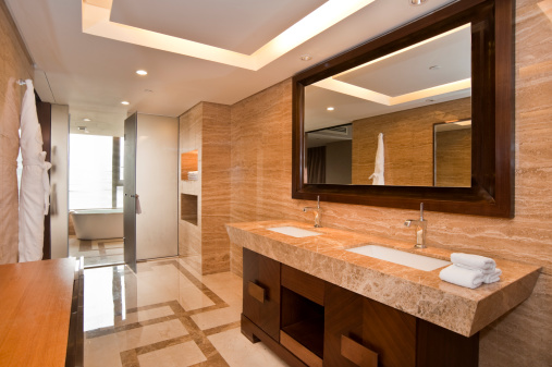 Luxury bathroom in a hotel room. Bathroom with bathtub, wash bowls, and reflections in mirror.