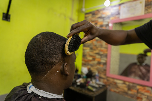 A barber brushes his client's hair during a haircut.