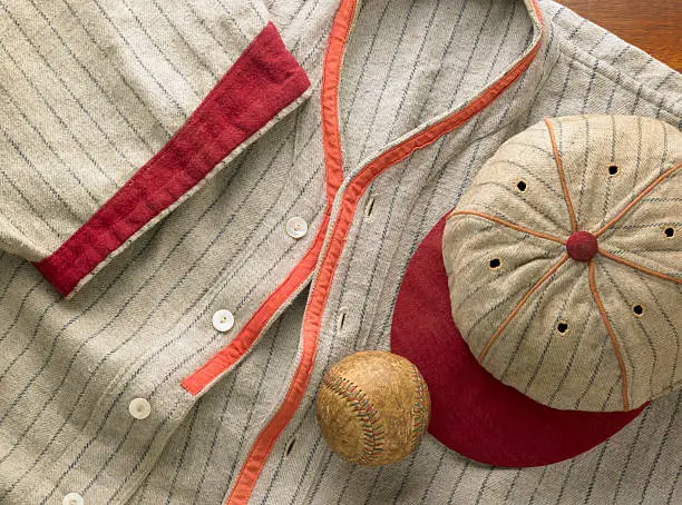 An antique pin-striped wool baseball uniform with a matching cap. Shot with an antique baseball.