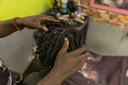 A barber fixes his client's braids in a salon in Africa.