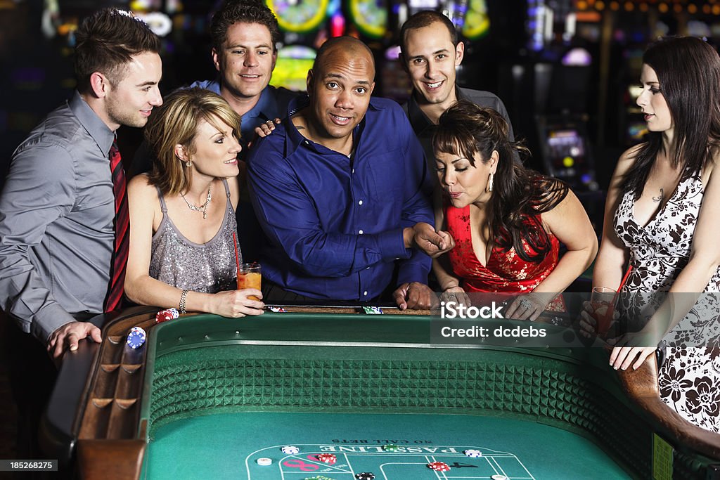 Diverse Group of People Playing Craps In Casino A diverse group of people playing at a craps table inside a casino. Craps - Dice Game Stock Photo