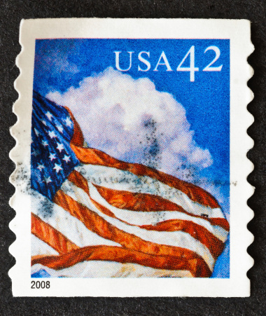 A postage stamp from 2008 showing a blowing U.S. flag against a sky of cumulus clouds