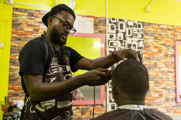 A barber is focused on cutting his client's hair in his salon A barber is focused on cutting his client's hair in his salon. black barber stock pictures, royalty-free photos & images