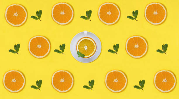 istock Half a orange, mint leaves and tea cup on the yellow background. Pattern. Flat lay. 1852688505