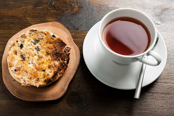 Cup of tea and round sandwich cookies with filling on a plate on white background, top view