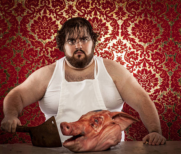 Butcher Cutting Pig's Head with Rusty Cleaver, Looking at Camera "Butcher Cutting Pig's Head with Rusty Cleaver, Looking at CameraThis creepy butcher is using a rusty cleaver to butcher a pig's head that looks like it's screaming in fear with its mouth and eyes wide open." grotesque stock pictures, royalty-free photos & images