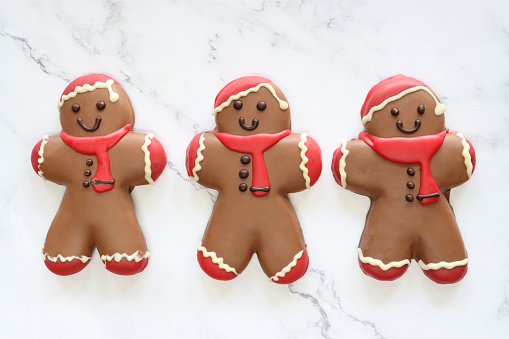 Stock photo showing elevated view of marble effect background with batch of homemade, Santa designed chocolate gingerbread men decorated with red and white royal icing.