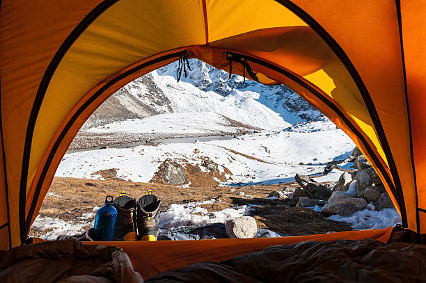 Looking out of tent to snowy mountains "Hiking boots outside a bright yellow dome tent looking through the entrance to crisp white mountains, glaciers and snoy Himalayan peaks. ProPhoto RGB profile for maximum color fidelity and gamut." base camp stock pictures, royalty-free photos & images