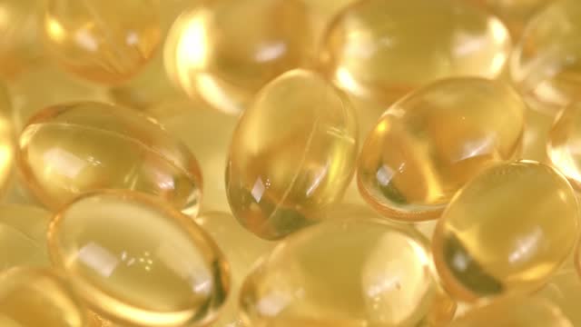 slow rotation of transparent yellow capsules with liquid Omega-3. closeup.