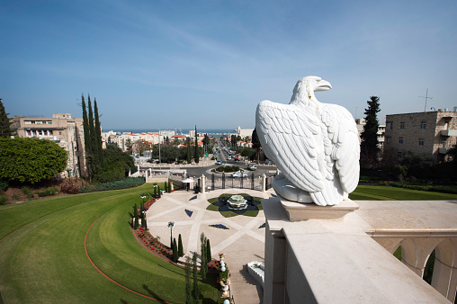 A statue of an eagle at the Bahia Gardens in Haifa, Israel.  The Mediterranean is seen in the distance.  