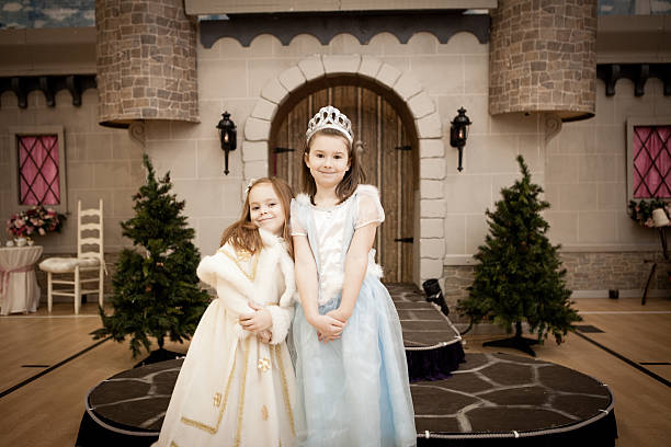 feliz sonriendo hermanas, vestido como princesses, con castillo de fondo - princess castle child family fotografías e imágenes de stock