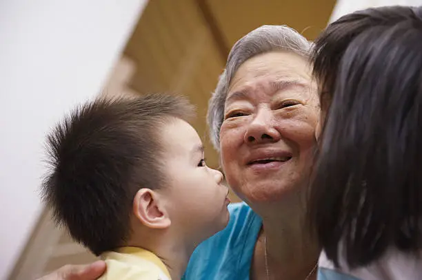 portrait of a grandmother being kissed by her grandchildren.