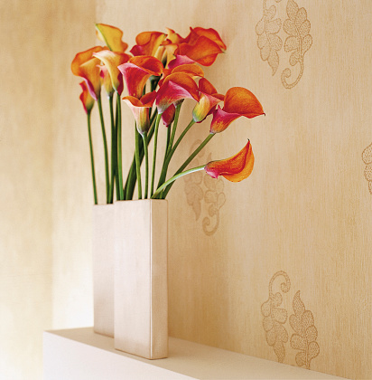 Arun lillies in a vase against stylish wallpaper.