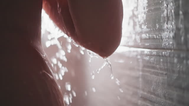 Lady stands in shower with droplets flowing down body