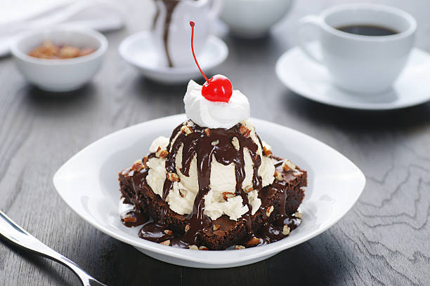 Brownie sundae with cherry on top and side cup of coffee Hot fudge brownie sundae. vanilla ice cream photos stock pictures, royalty-free photos & images