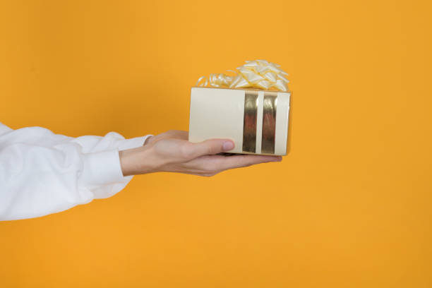 istock hand with gift box and ribbon on color background 1852728810
