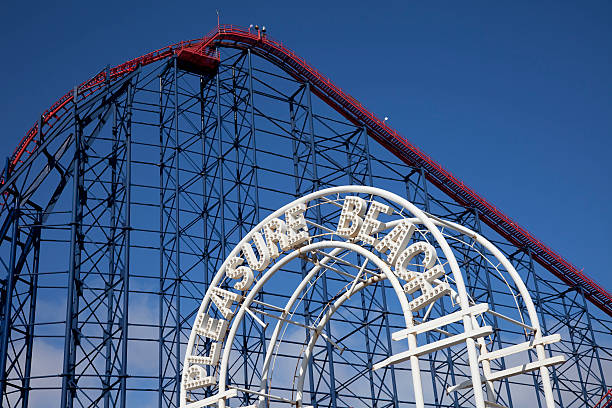 Blackpool Pleasure Beach rollercoaster "An entrance sign for Blackpool Pleasure Beach, with part of The Pepsi Max Big One rollercoaster behind. Blackpool is a traditional seaside town in Lancashire, UK." lancashire photos stock pictures, royalty-free photos & images