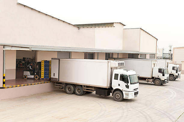 Three white trucks in front of a warehouse worker loading plastic crates in truck cold storage stock pictures, royalty-free photos & images