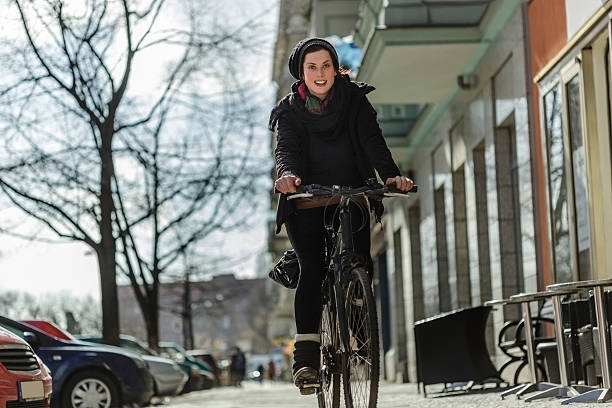 Woman Commuting by Bicycle Woman commuter riding her bicycle on a Berlin city street.   moabit stock pictures, royalty-free photos & images