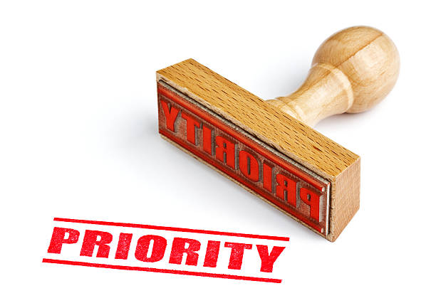 A wooden stamp about priority in a white background “PRIORITY” rubber stamp. Clipping path on rubber stamp. important message stock pictures, royalty-free photos & images