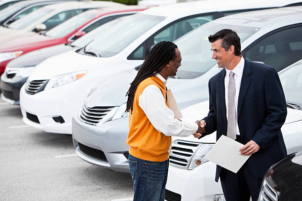 Customer shaking hands with car salesman African American man (40s) shaking hands with car salesman.  Shallow DOF, focus on foreground. car for sale stock pictures, royalty-free photos & images