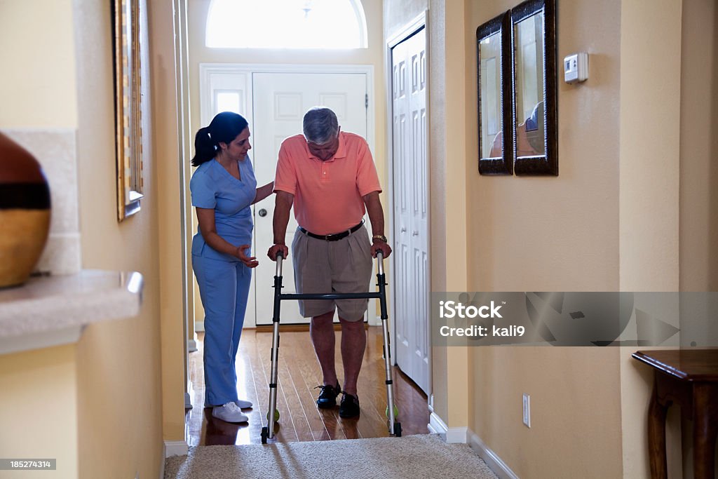 Operatore sanitario domiciliare con uomo anziano con Deambulatore - Foto stock royalty-free di Assistente domiciliare