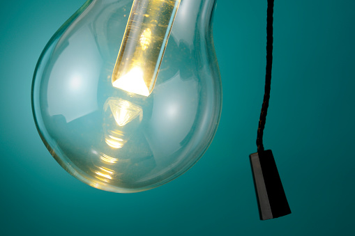 Close-up of illuminated LED light bulb against blue background with string.