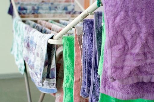 Clean laundry hanging on drying rack indoors. Close-up, selective focus.