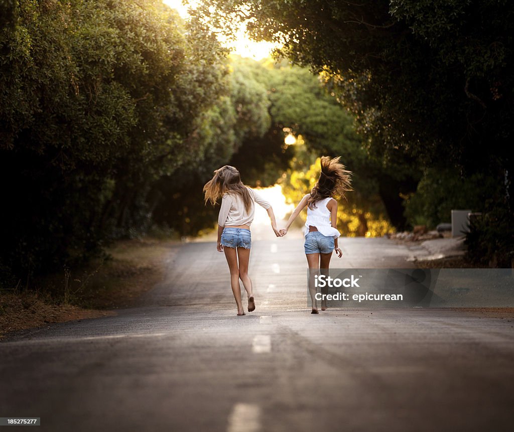 Deux belles jeunes femmes en bonne santé sauter ensemble le long de la route - Photo de 18-19 ans libre de droits