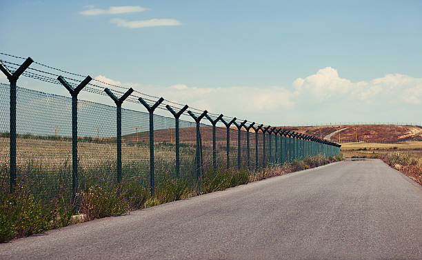 road рядом с забор - barbed wire фотографии стоковые фото и изображения