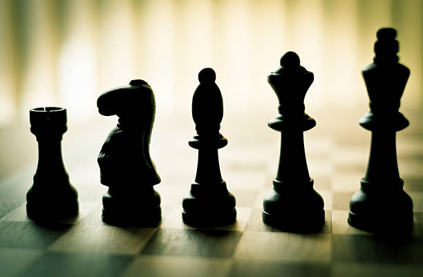 Row of back lit chess pieces on chess board