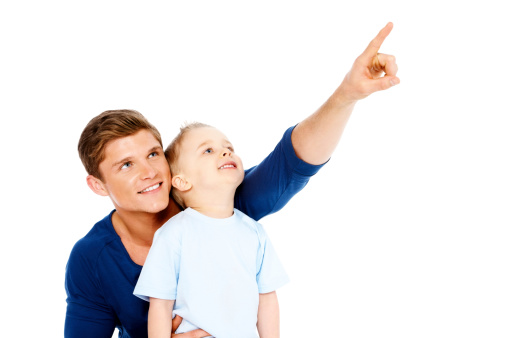 Portrait of a young father pointing away and showing something to his son against white background