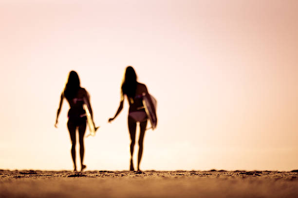 curvy silhouettes des deux femmes de sortir pour le surf - surfing teenage girls friendship sunset photos et images de collection